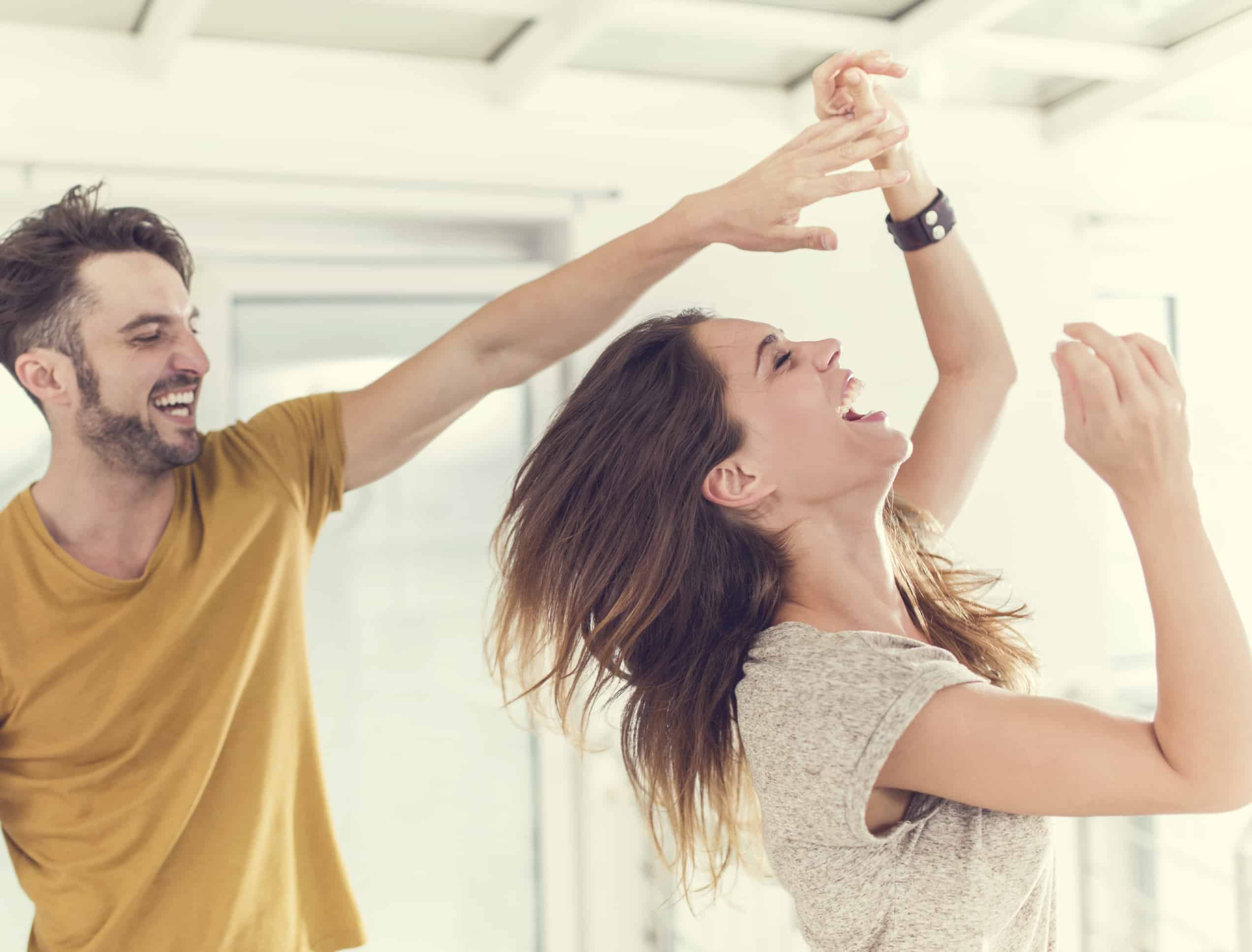 Trening for hjernens helse 1 Lykkelig ungt par som danser hjemme og ler.