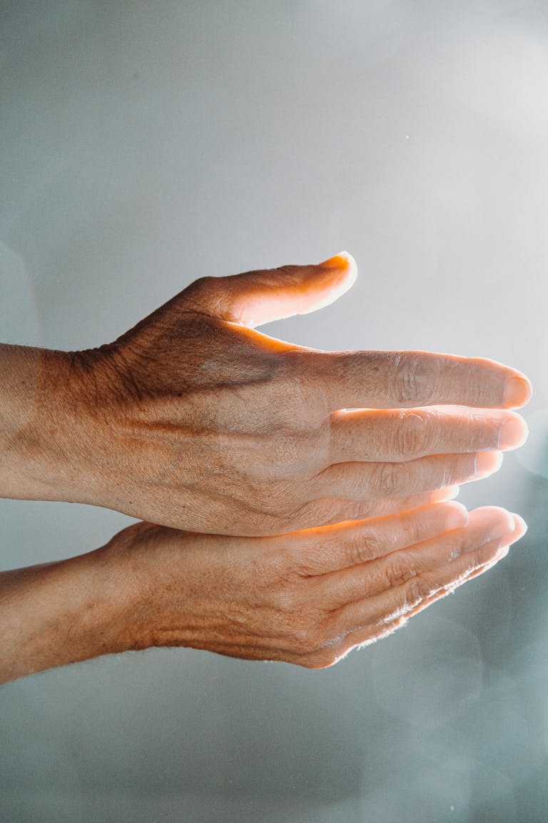 A close-up of human hands illuminated by sunlight, showcasing skin texture and warmth.