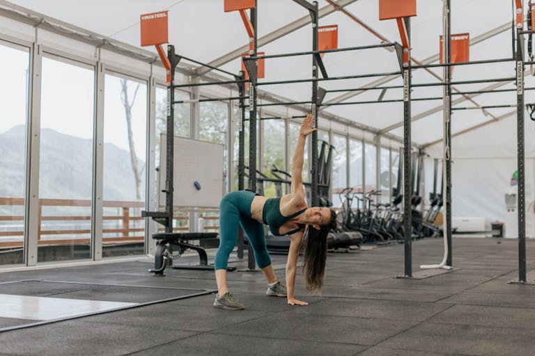 Caucasian woman stretching in a modern gym environment, promoting fitness and exercise.